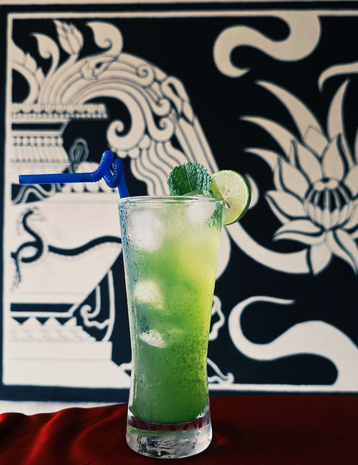 A mint mojito in front of a black and white Newari mural